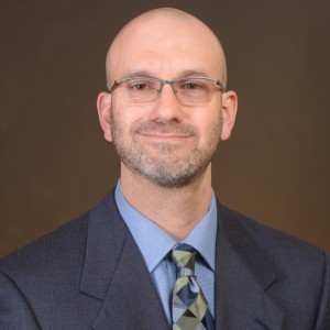 researcher Joshua Abbott wearing glasses and a blue suit