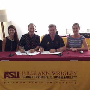 Two men and two women smile as an agreement is signed