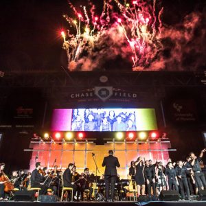 Fireworks light up the sky over a band onstage at a baseball park