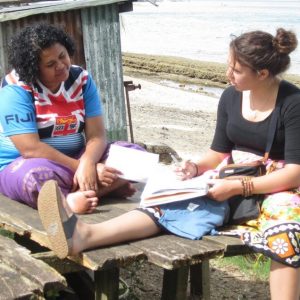 An SOS students sits, interviewing a Fijian woman, also seated.