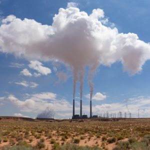 Three smoke stacks at a power plant with billowing smoke in northern Arizona
