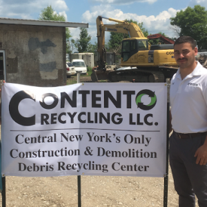 Anthony Contento stands near a sign for his business, Contento Recycling