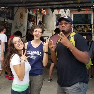 3 ASU students show ASU pitchfork hand signals on a street in Cuba