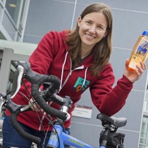 Woman holding a water bottle standing near bike