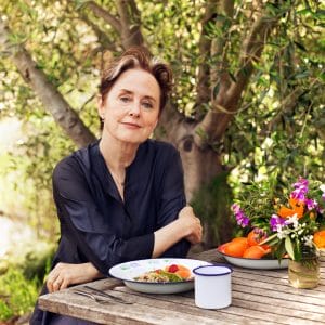 Alice Waters sitting at table outdoors with a meal in front of her.