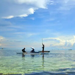 Three people on a canoe floating on clear water