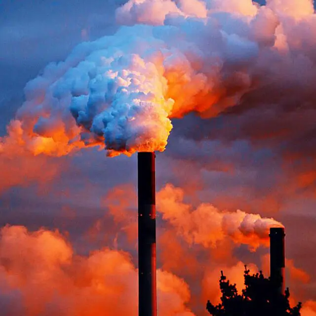 Sunset with smokestack in the foreground emitting pollutants.