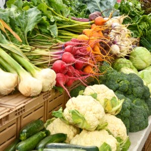 Store display of vegetables including onions, radishes, carrots, cauliflower, broccoli, etc.