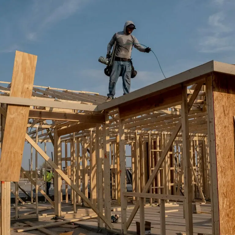 Construction worker standing on top of house being built, working in the heat