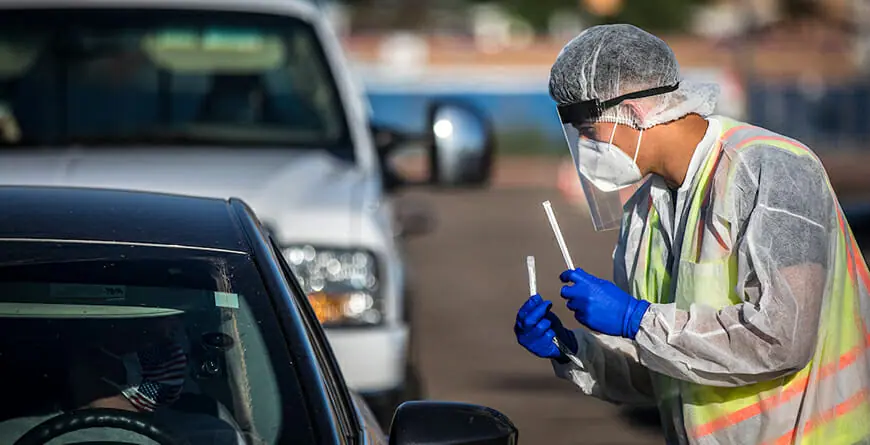 Volunteer administering COVID-19 test in drive through testing site.