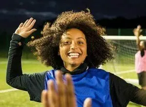 Girl giving a high five to person out of photo at at soccer game