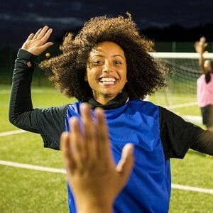 Girl giving a high five to person out of photo at at soccer game