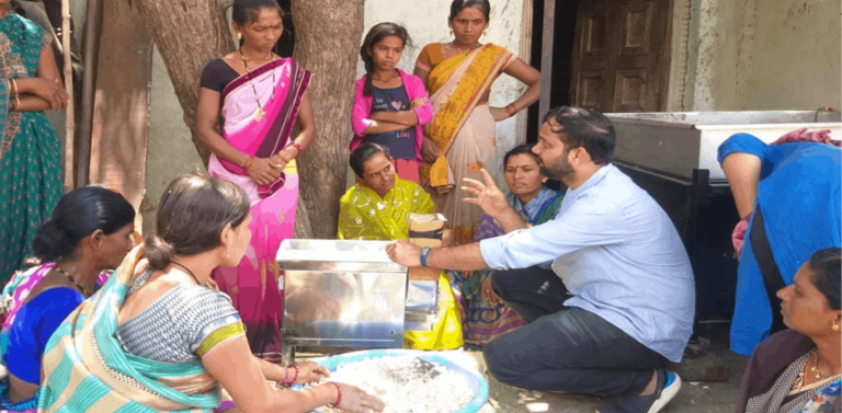 Man showing a group of Indian women how to use the solar food processing unit