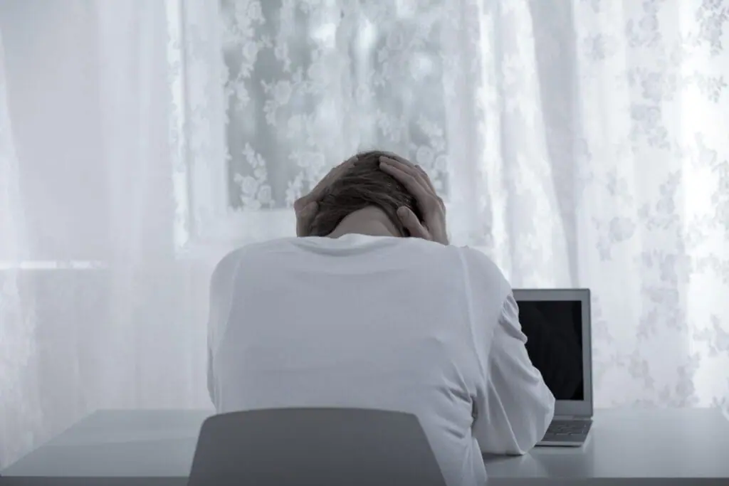 Person sitting at a computer looking stressed
