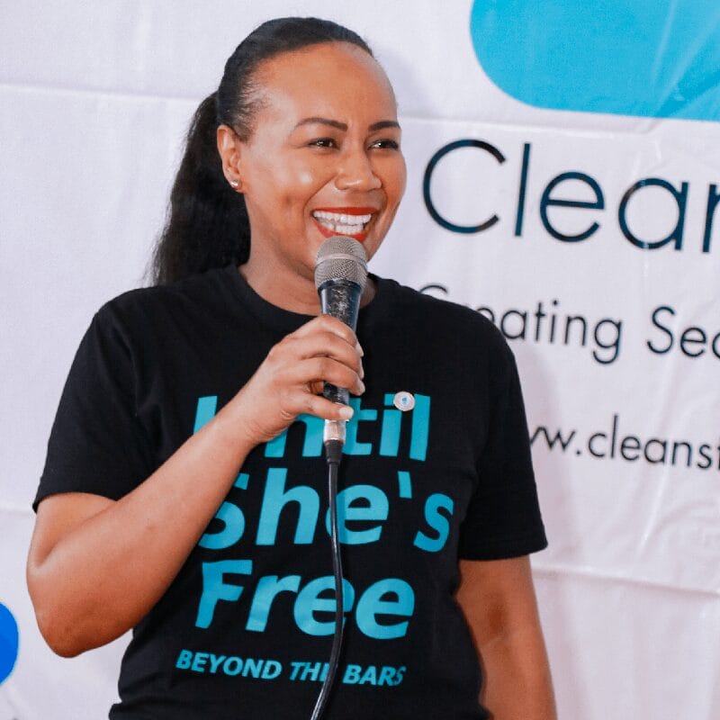 Teresa Njoroge speaking into a microphone she is holding.