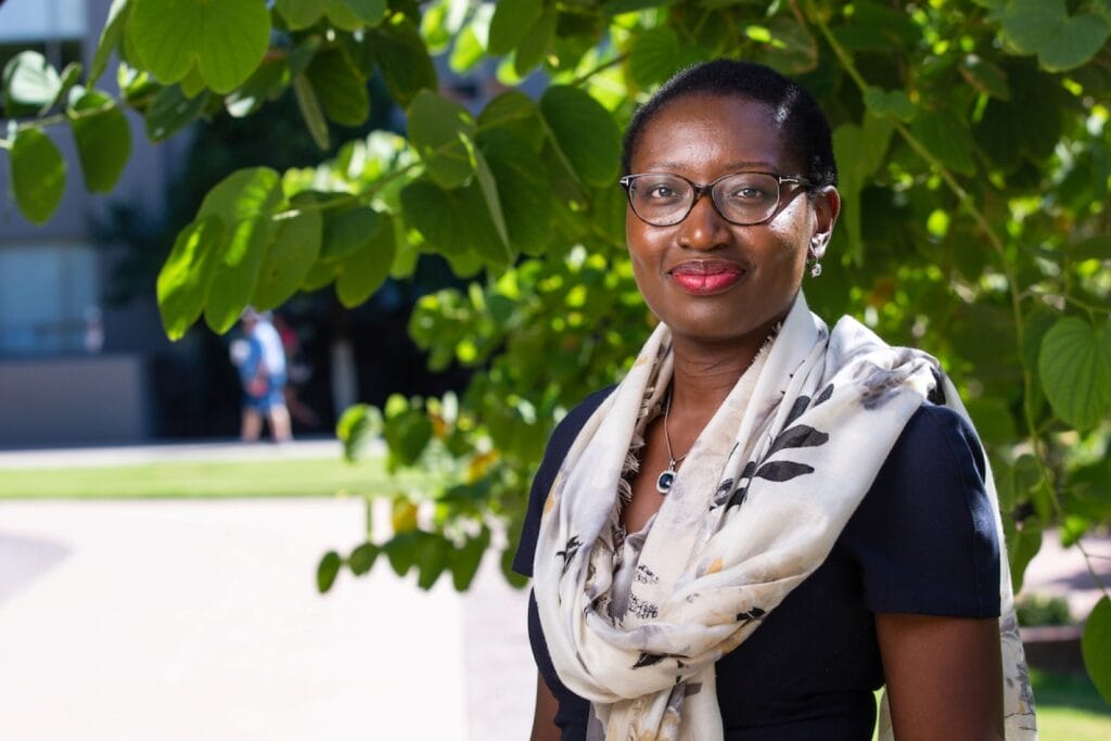 Dr. Timiebi Aganaba standing next to a tree, smiling.