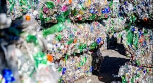 Bales of compressed plastic bottles stacked in a recycling area.